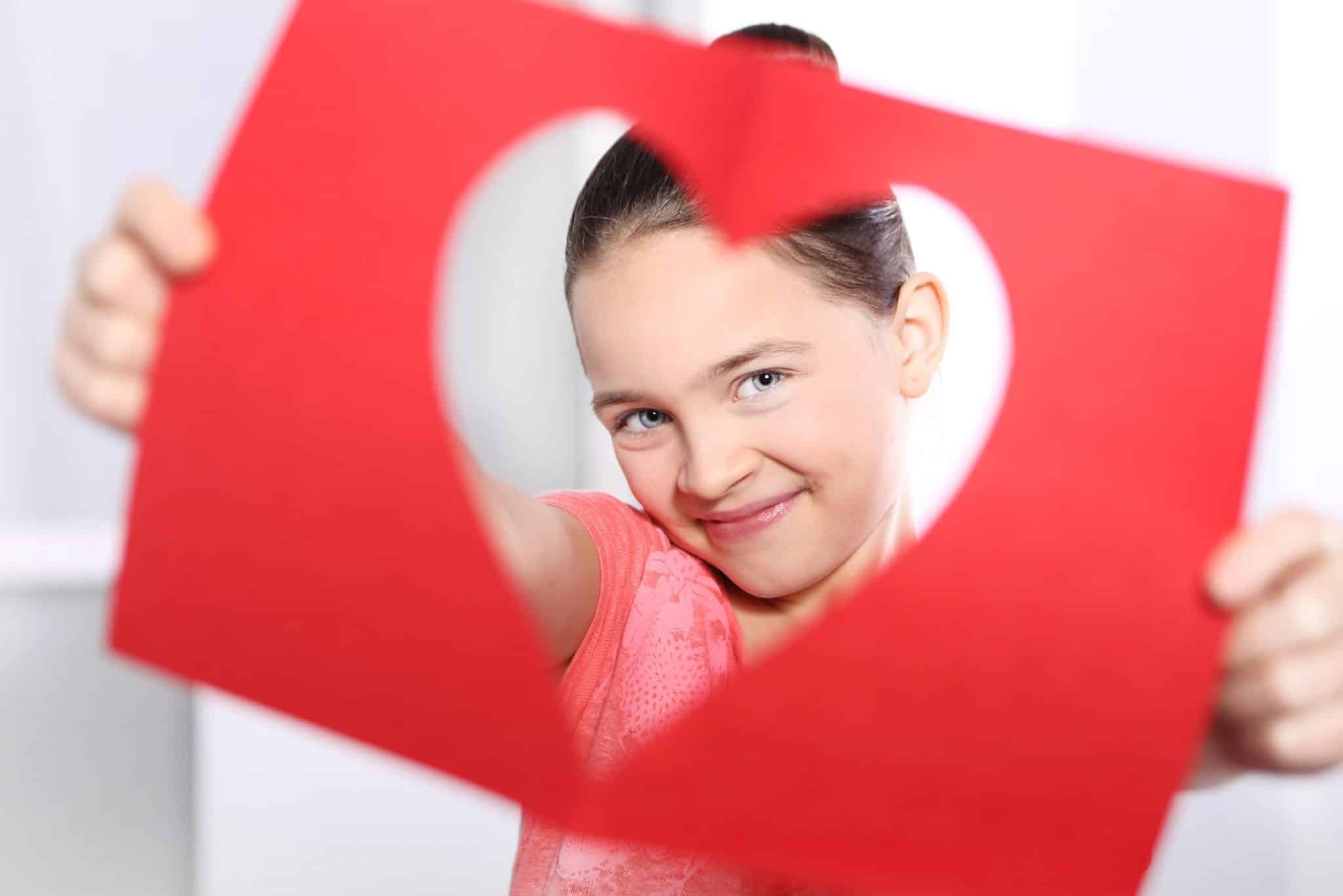 Girl Smiling Through a Heart-Shaped Hole in Paper