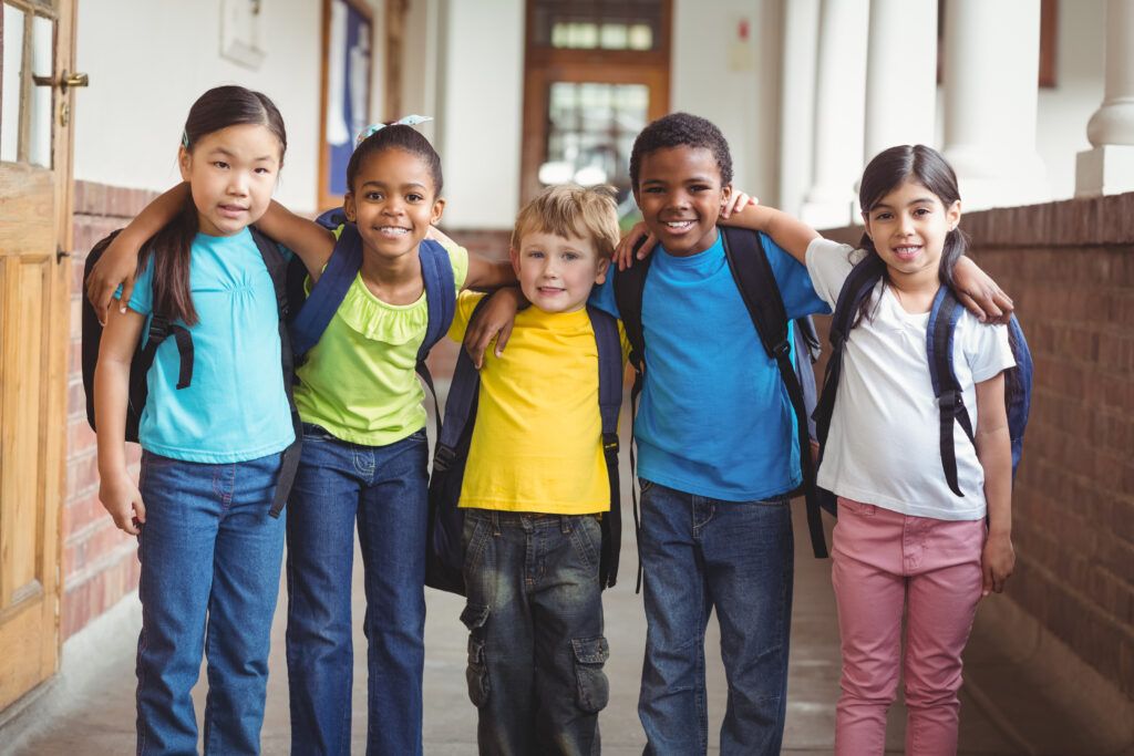 cute pupils with schoolbags standing at corridor in school.